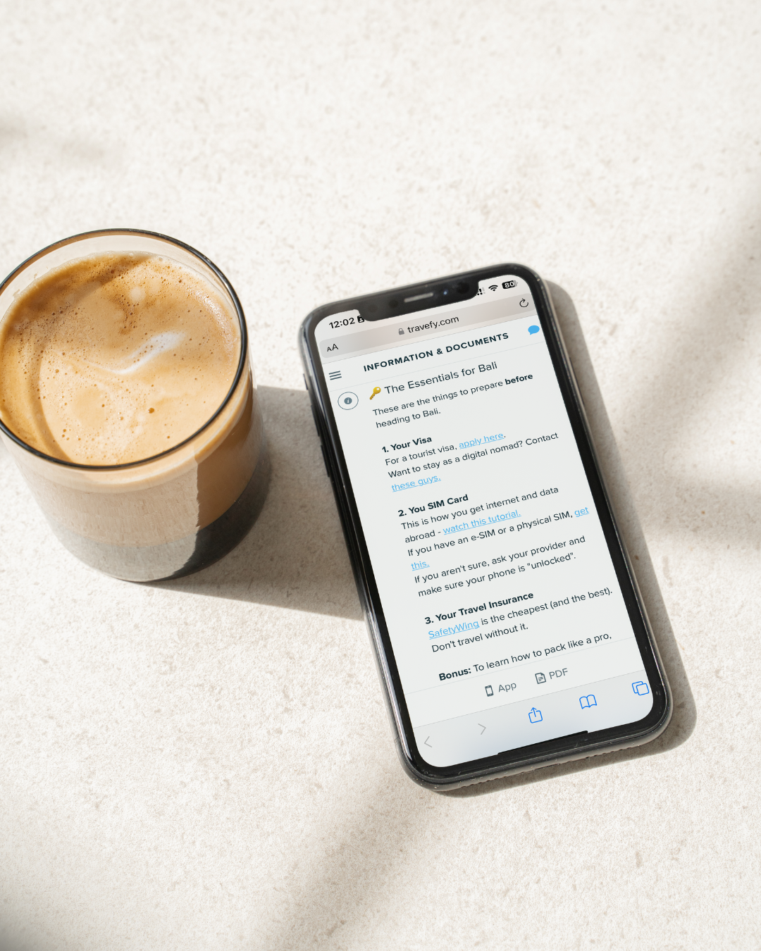 Smartphone displaying a document on a light surface with a glass of coffee.