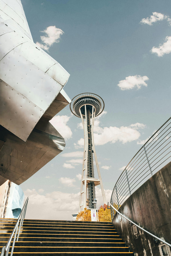 Space Needle against a blue sky with clouds, viewed from a low angle.