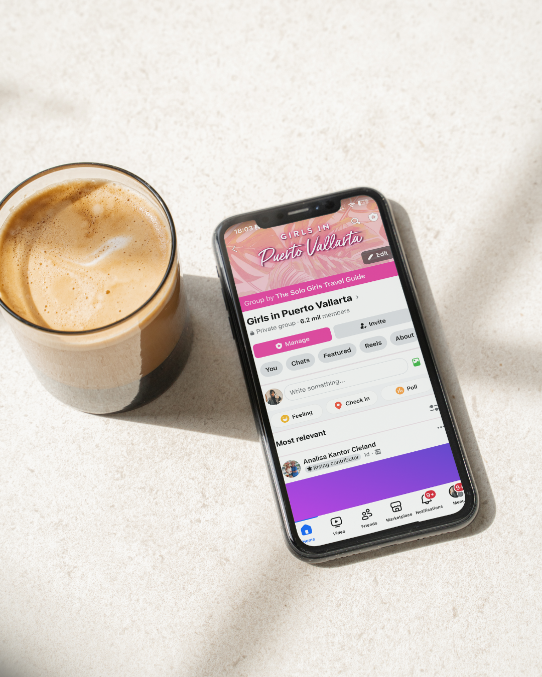 Phone displaying a dating app on a white surface with a cup of coffee