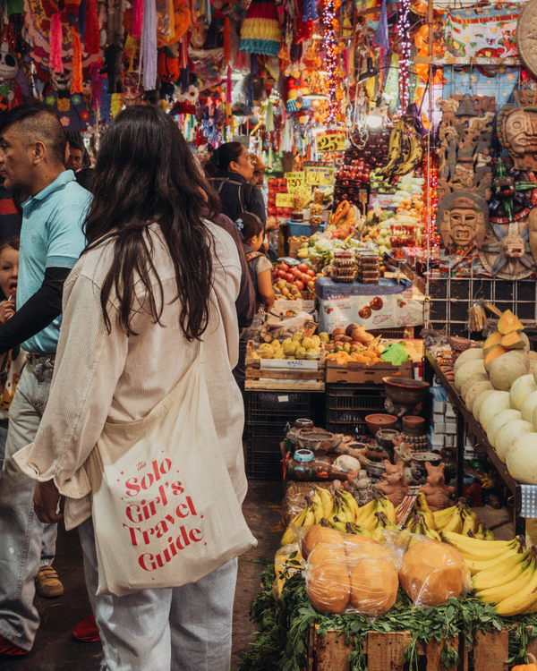 Person shopping in a colorful market with produce and decorations.