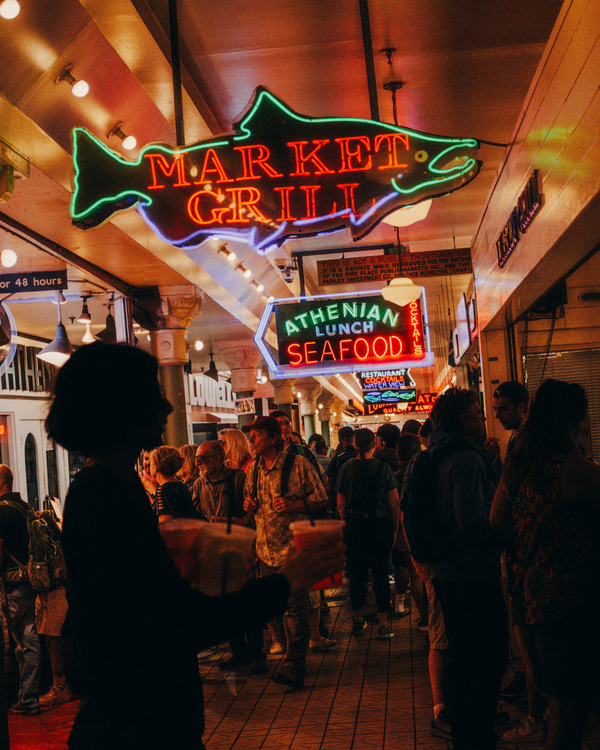 Neon signs in a market setting with people walking around