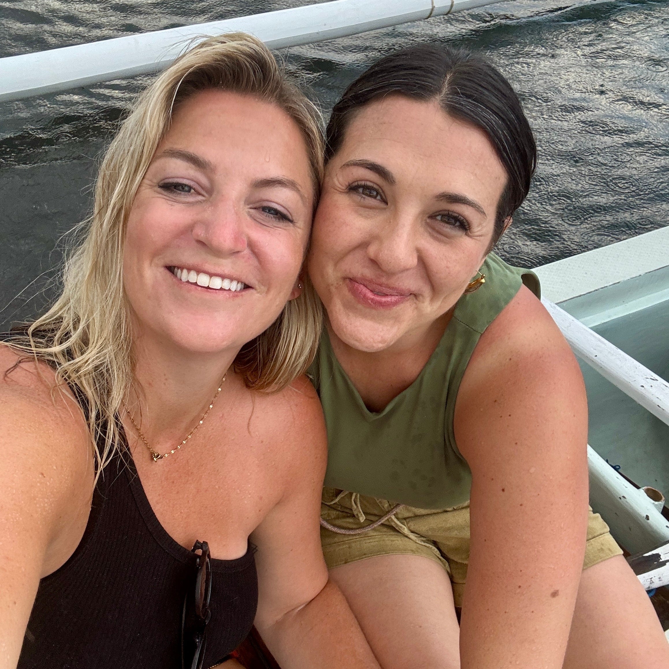 Two women sitting on a boat with water in the background