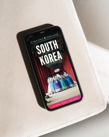 A smartphone displaying the cover of a travel guidebook to South Korea, with a visible stage and performers.
