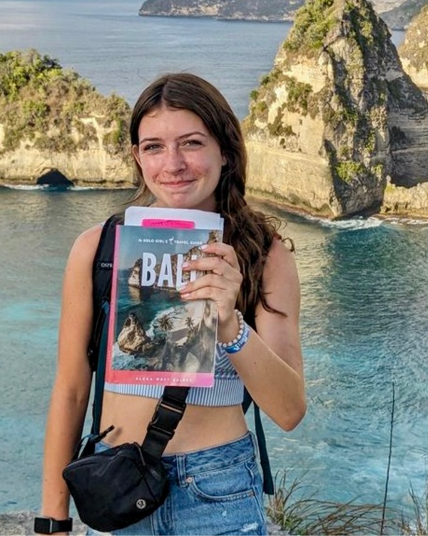 woman in a beach with bali travel guide in her hand
