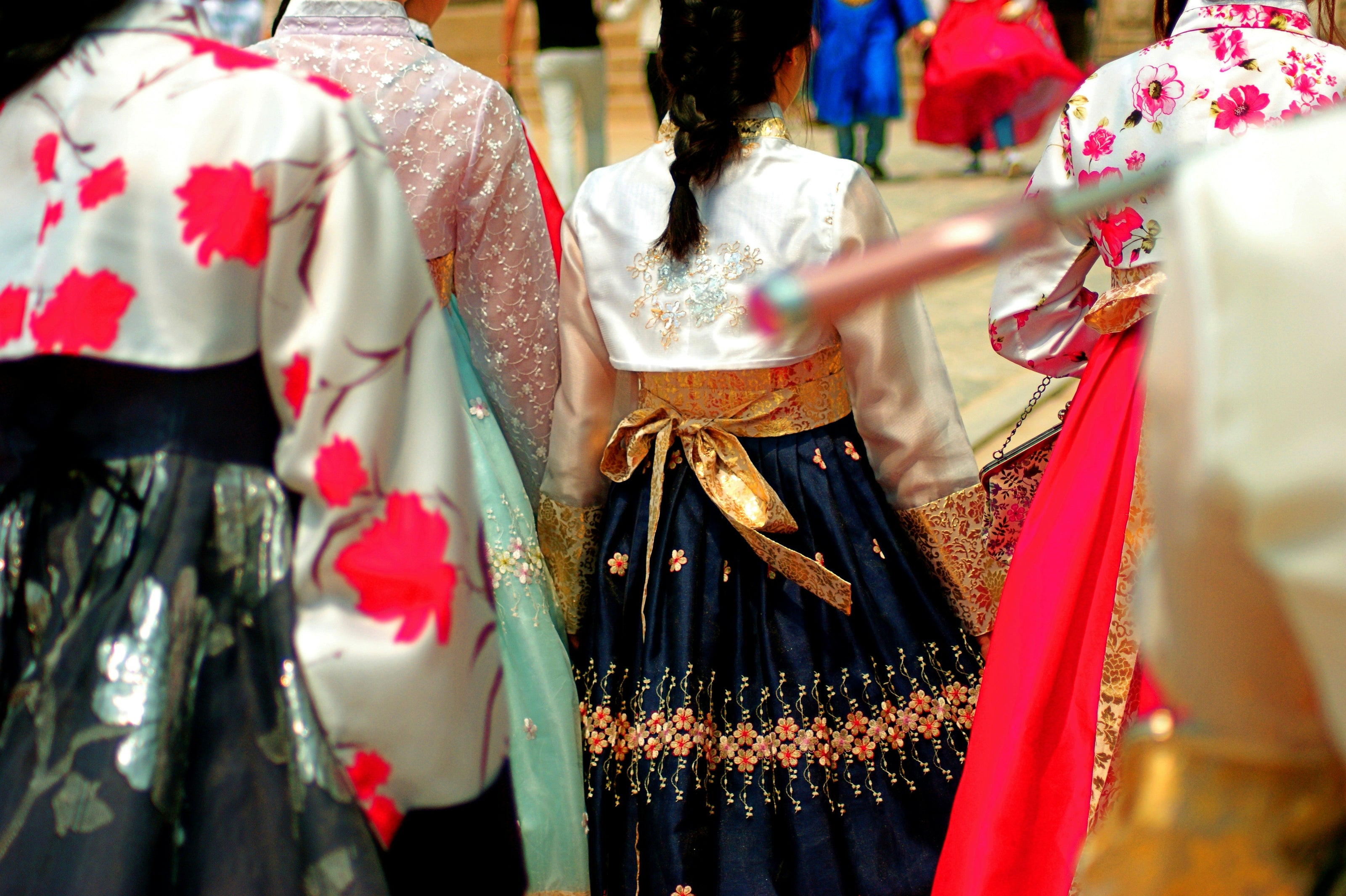 Traditional Korean hanbok with floral patterns worn by people in an outdoor setting.