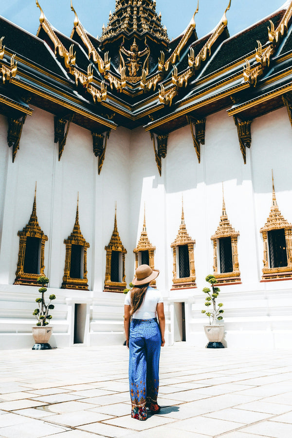 Woman standing in front of a temple with intricate architecture in Thailand
