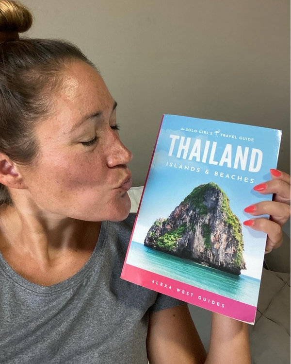 reader alongside her copy of the thailand islands and beaches travel guide by the solo girls travel guide