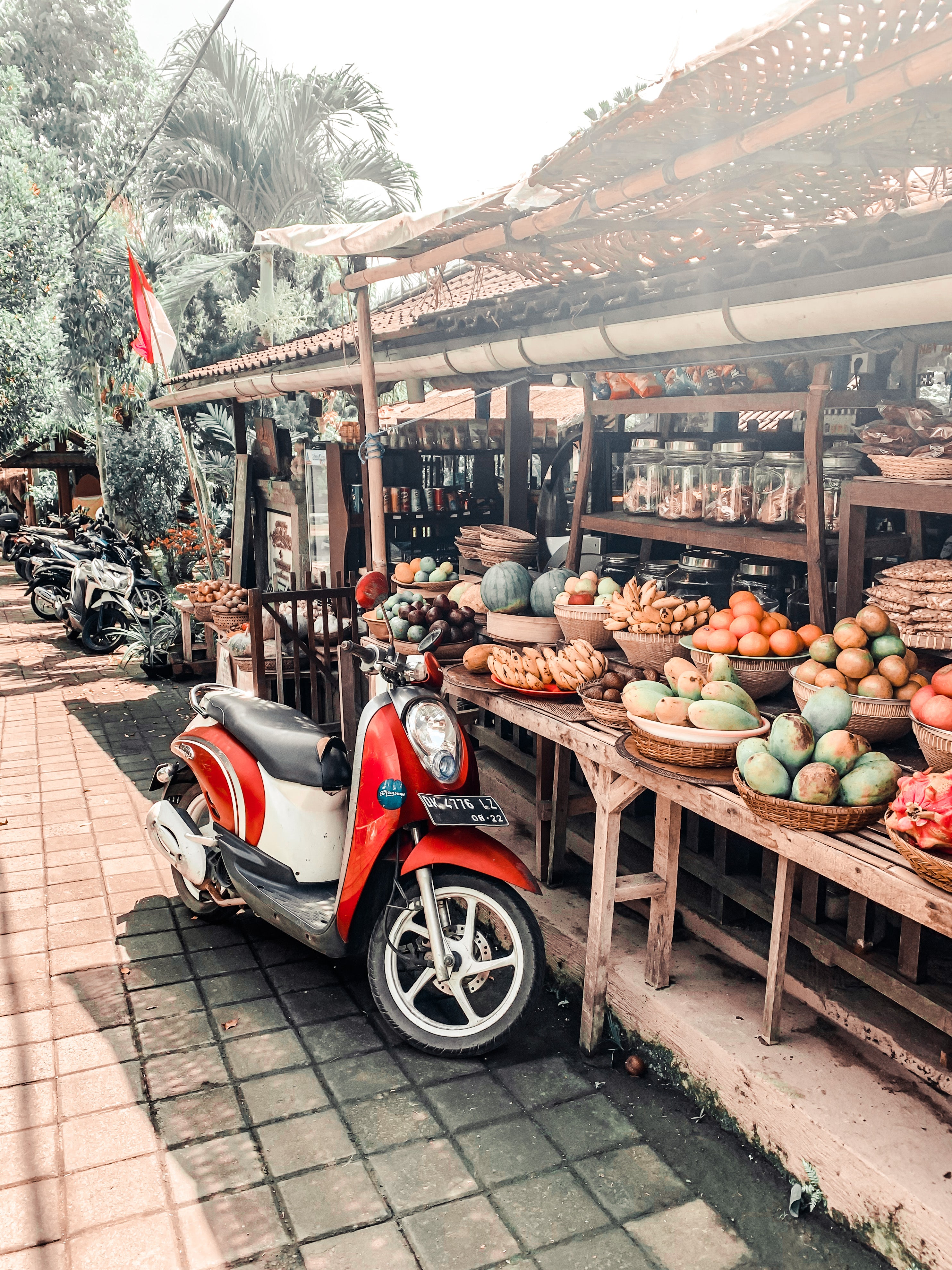Outdoor market stall with various fruits and a scooter parked nearby.