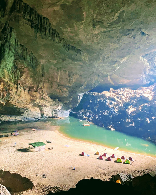 Cave entrance with a scenic view of mountains and water
